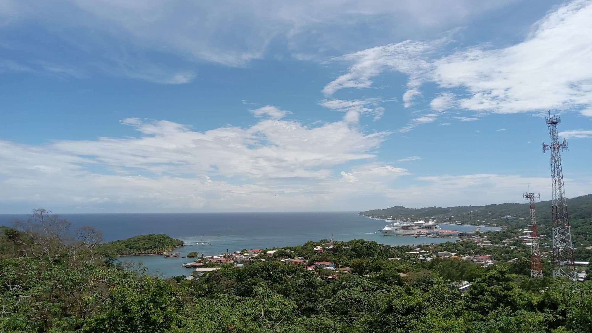 A hilltop view over Coxen Hole with a cruise ship docked at the port and the Caribbean beyond